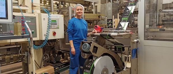 Arbeiterin in blauer Kleidung an Verpackungsmaschine