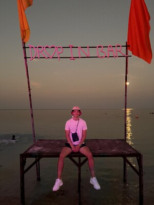 Link: Großansicht des Bildes - Bildinhalt: Person bei Sonnenuntergang unter Drop In Bar Schild