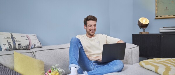 Person arbeitet entspannt mit Laptop auf Sofa