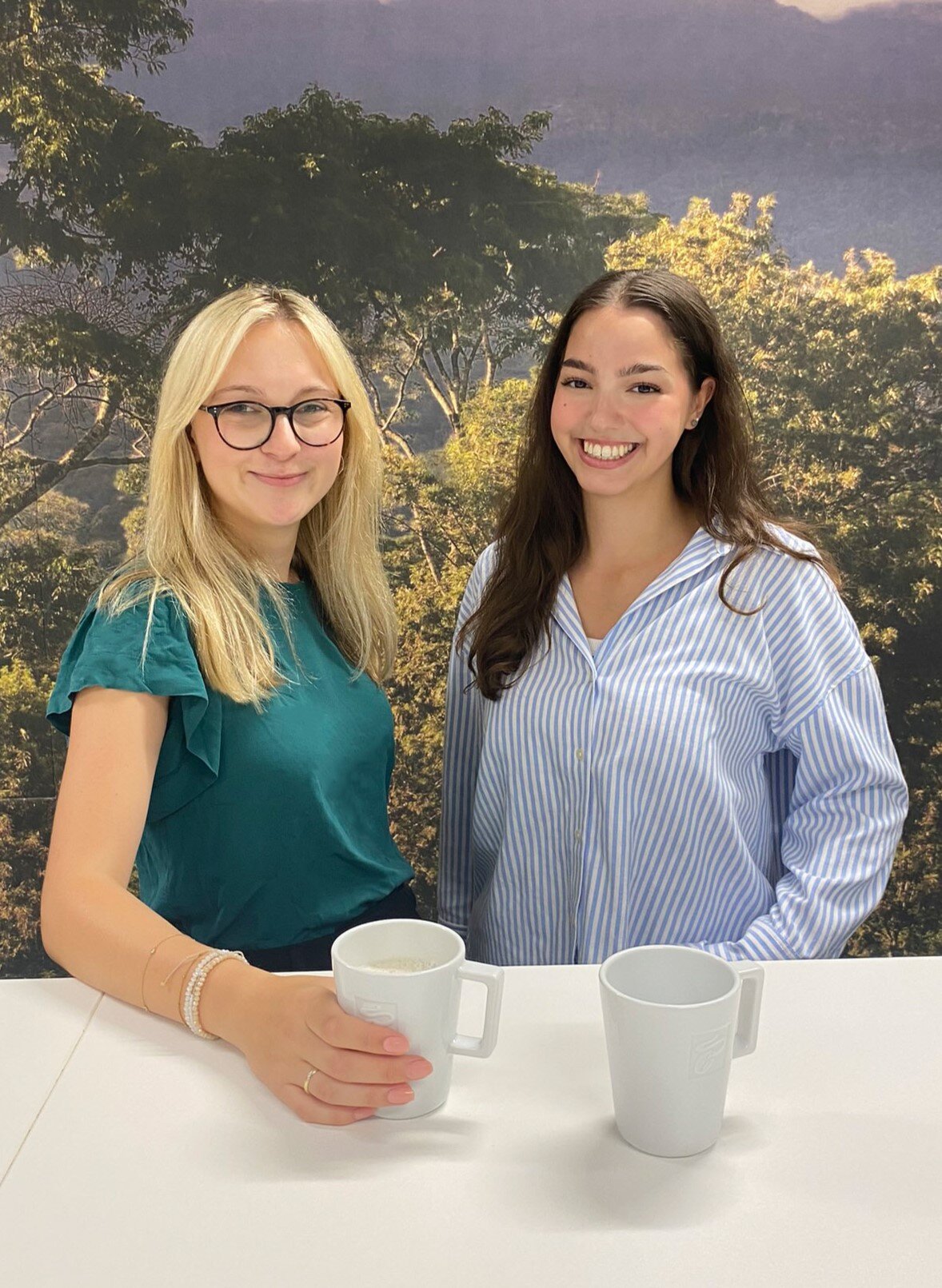Zwei Frauen mit Kaffeetassen vor Waldhintergrund