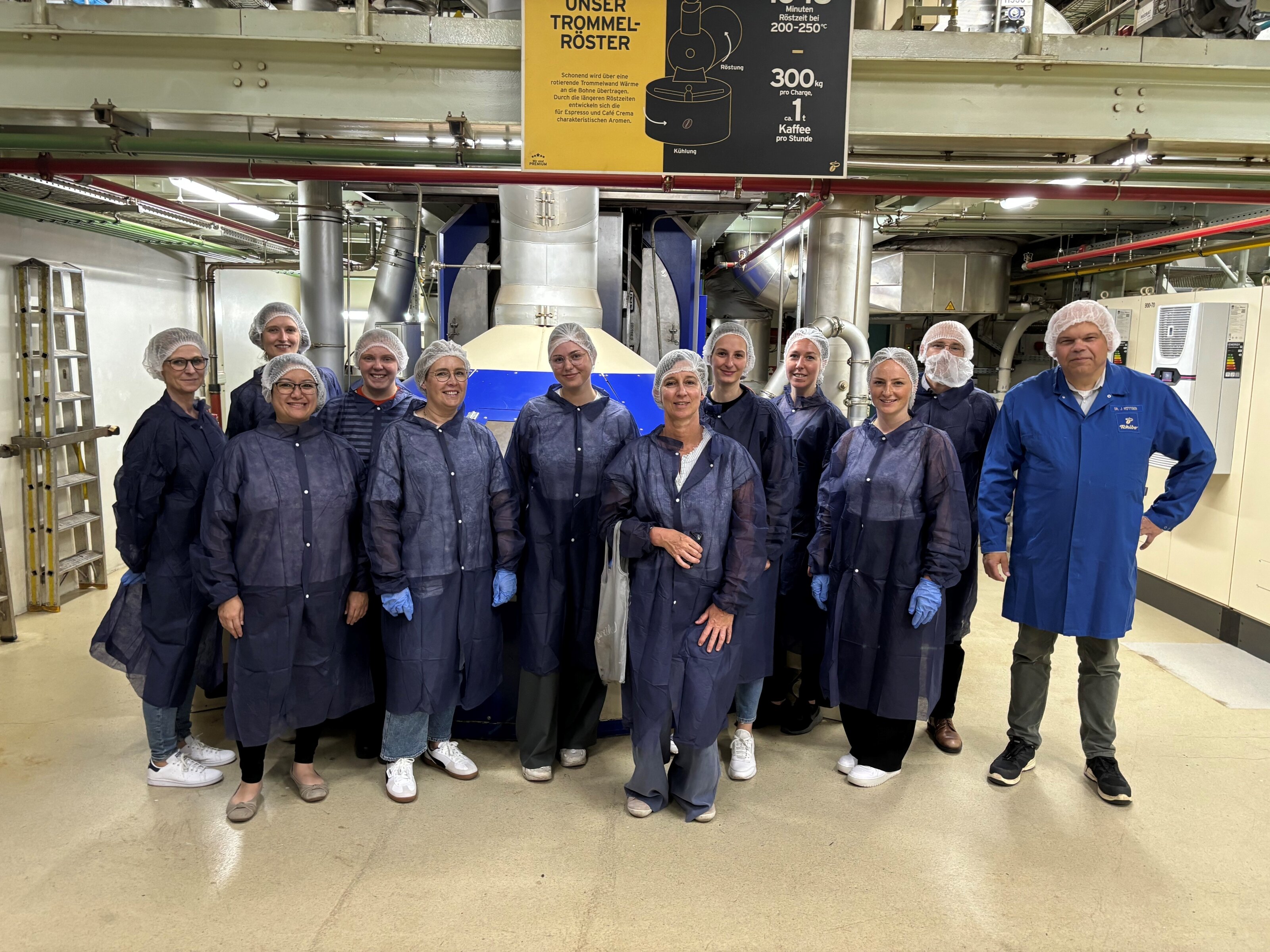 Gruppe in Schutzkitteln vor Industrieröstmaschine