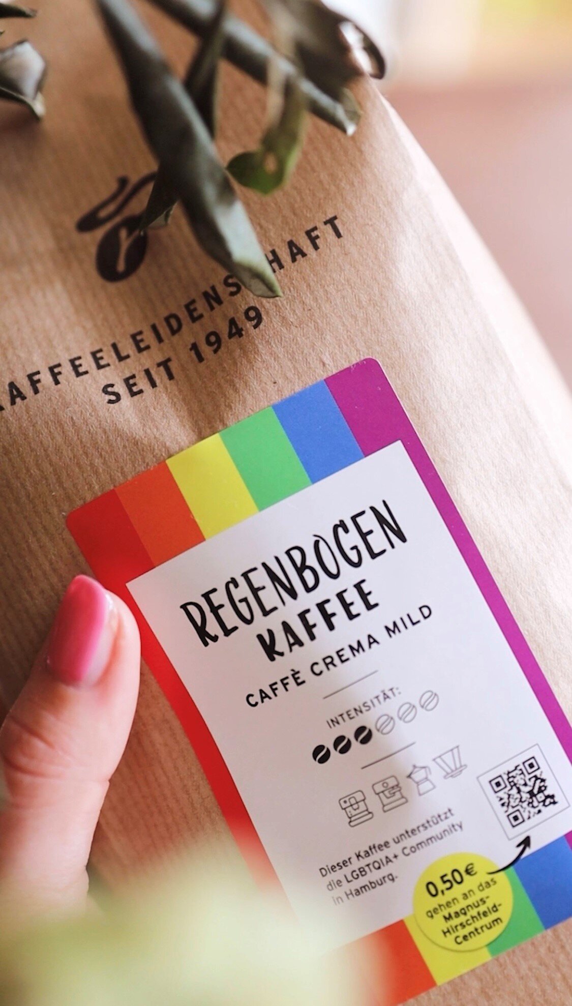 Hand hält Regenbogen Kaffee in brauner Tüte