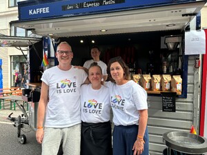 Link: Großansicht des Bildes - Bildinhalt: Drei Personen mit „Love is Love“-Shirts vor Kaffeewagen
