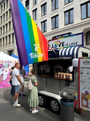 Link: Großansicht des Bildes - Bildinhalt: Tchibo-Kaffeestand mit Regenbogenflagge und Kunden