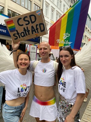 Link: Großansicht des Bildes - Bildinhalt: Drei Menschen bei CSD mit Regenbogenfahnen