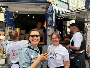 Link: Großansicht des Bildes - Bildinhalt: Menschen vor Pride-Foodtruck mit Regenbogenfahnen
