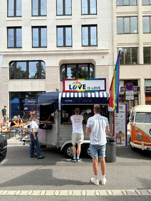 Link: Großansicht des Bildes - Bildinhalt: Kaffeestand mit „Love is Love“-Schild und Regenbogenflagge