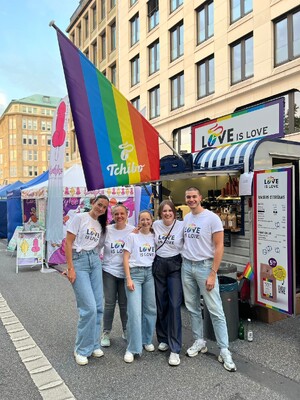 Link: Großansicht des Bildes - Bildinhalt: Fünf Menschen vor Tchibo-Stand mit Regenbogenflagge