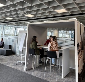 Link: Großansicht des Bildes - Bildinhalt: Drei Personen sitzen an Hochtisch im Großraumbüro
