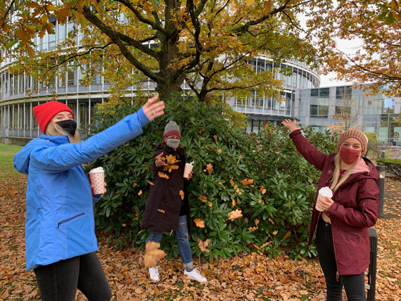 Drei Menschen werfen Herbstlaub im Park