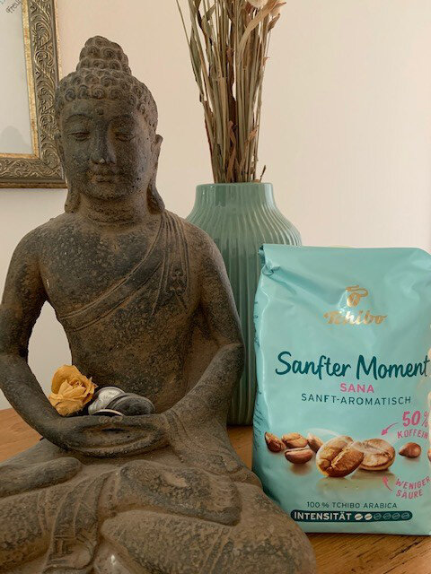 Buddhafigur neben Tchibo-Kaffeepackung