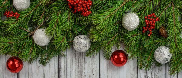 Tannenzweige mit roten Beeren und Christbaumkugeln