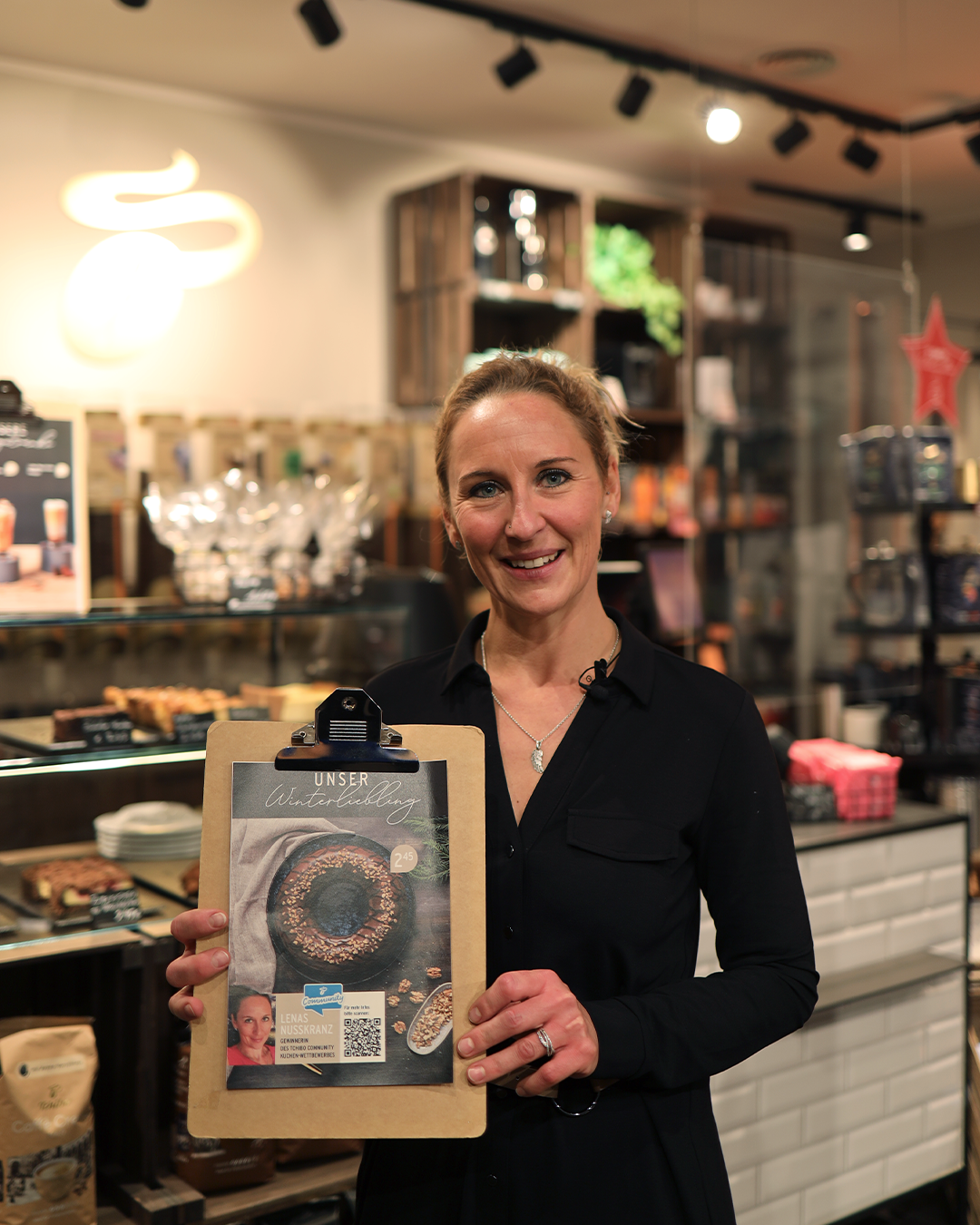 Frau im Café hält Klemmbrett mit Kuchenplakat