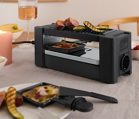 Kleiner Raclette-Grill mit Pfännchen auf Tisch