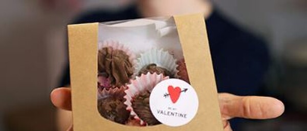 Hand hält Pralinenschachtel mit Valentinsaufkleber