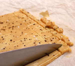 Link: Großansicht des Bildes - Bildinhalt: Messer schneidet karamellige Fudge-Streifen