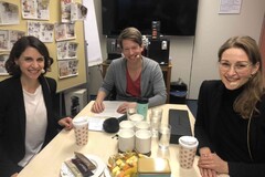 Drei Personen bei Besprechung mit Kaffee und Snacks