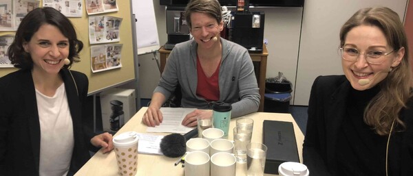 Drei Personen bei Besprechung mit Kaffee und Snacks
