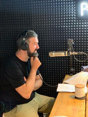 Person mit Kopfhörern im Tonstudio am Mikrofon