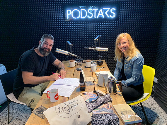 Zwei Personen im Podcaster-Studio am Holztisch