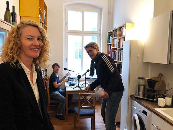Drei Personen mit Mikrofonen in kleiner Küche
