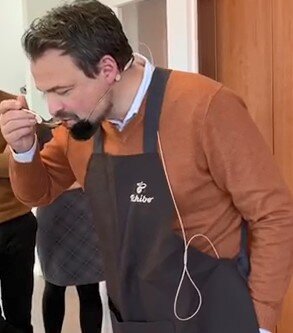 Person mit Schürze trinkt aus einer Tasse