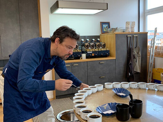 Mann verkostet Kaffee aus vielen Tassen