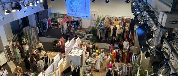 Modemesse mit Ständen, Kleiderstangen und Besuchern