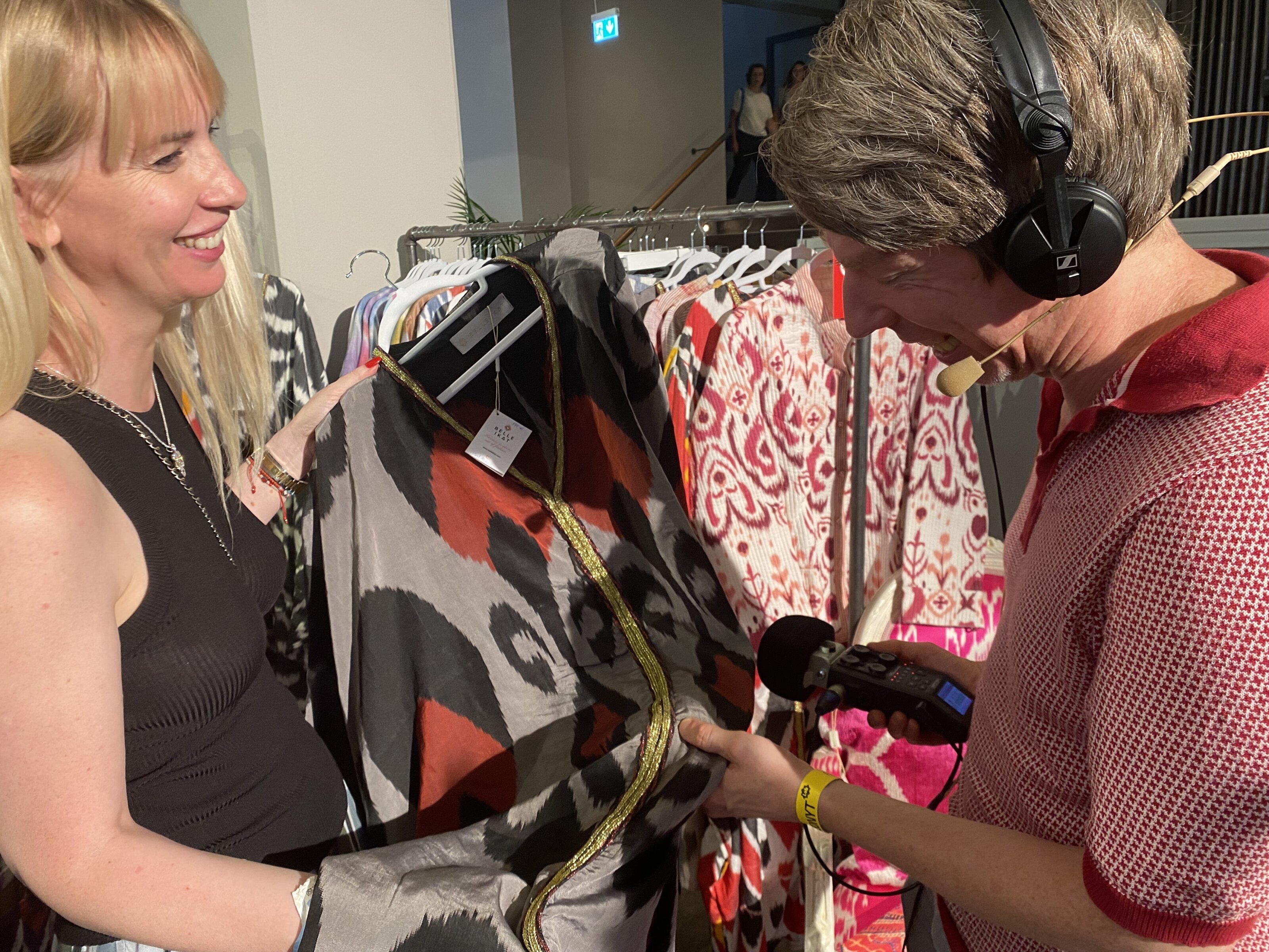 Reporter mit Mikrofon betrachtet buntes Kleid