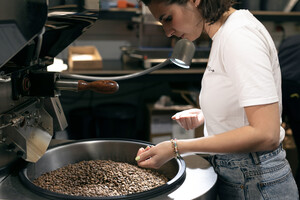 Link: Großansicht des Bildes - Bildinhalt: Person prüft Bohnen in Kaffeeröstmaschine