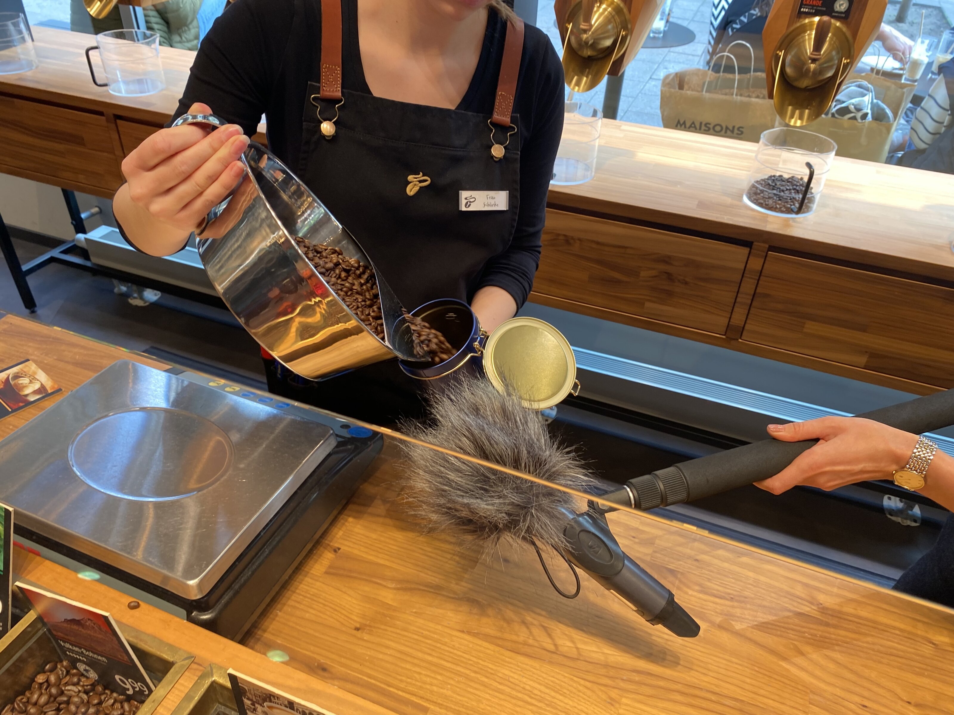 Barista füllt Kaffeebohnen, Mikrofon nimmt auf