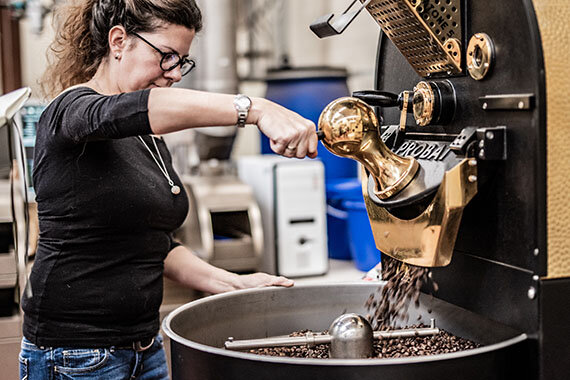Frau röstet Kaffeebohnen in großer Maschine