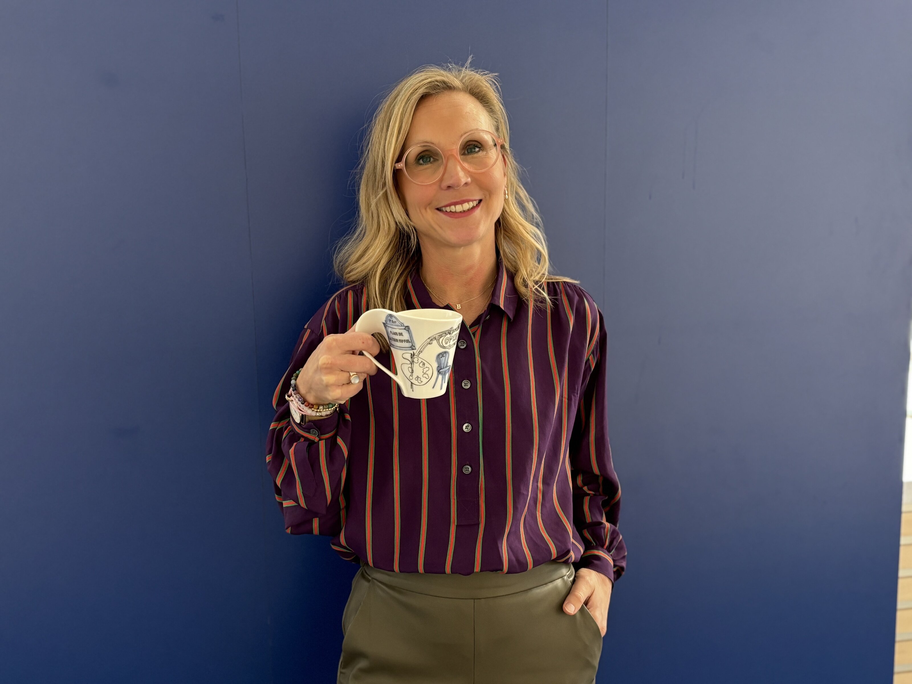 Person mit Tasse vor blauem Hintergrund