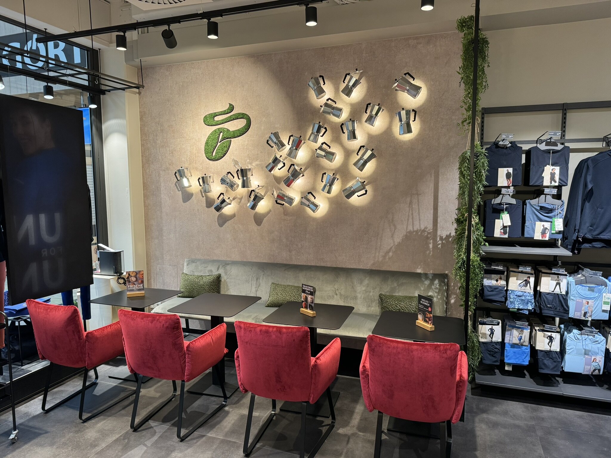 Café-Ecke im Laden mit roten Stühlen und Wanddeko