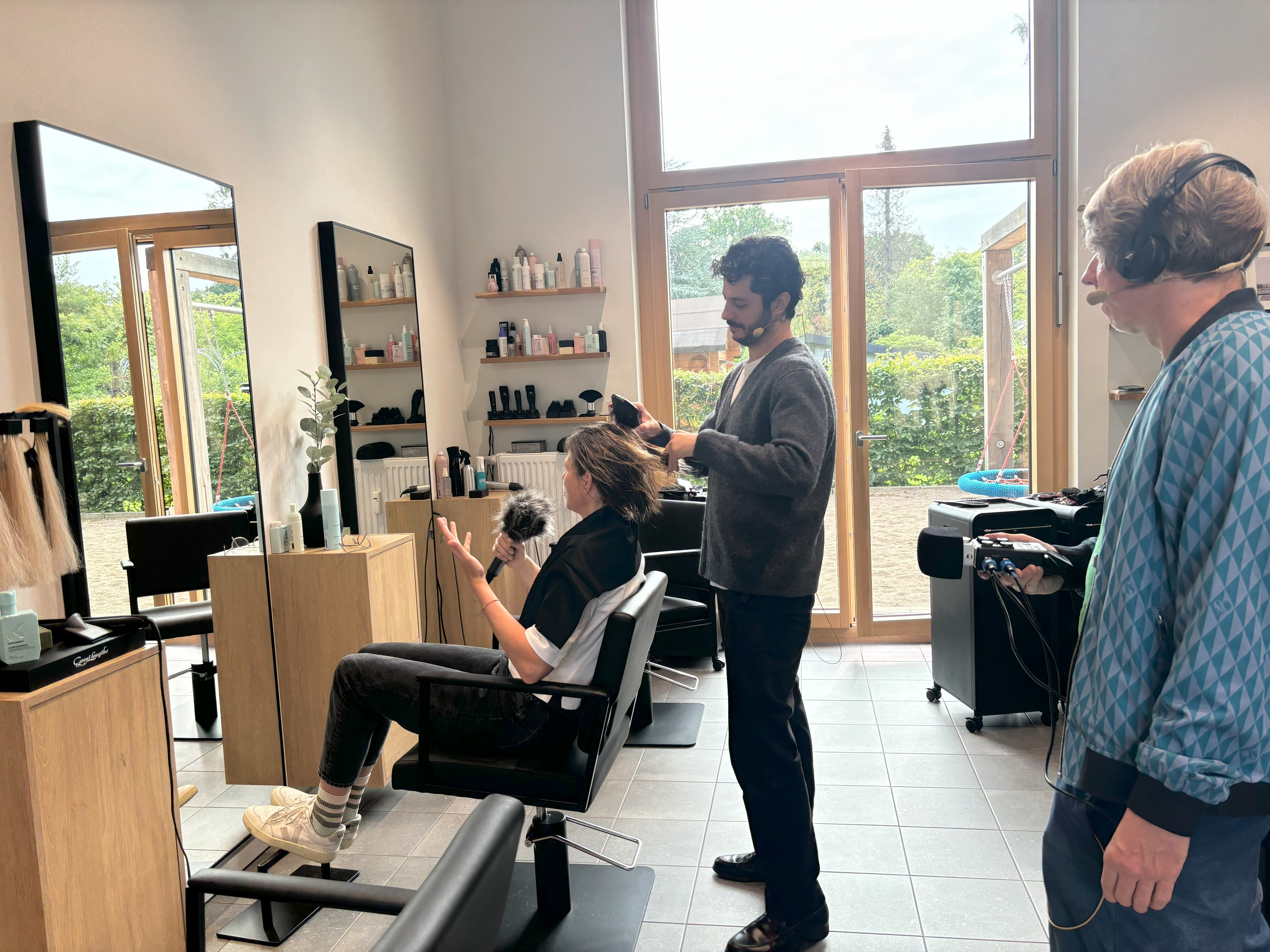 Person beim Haareschneiden, Tonmann filmt im Salon