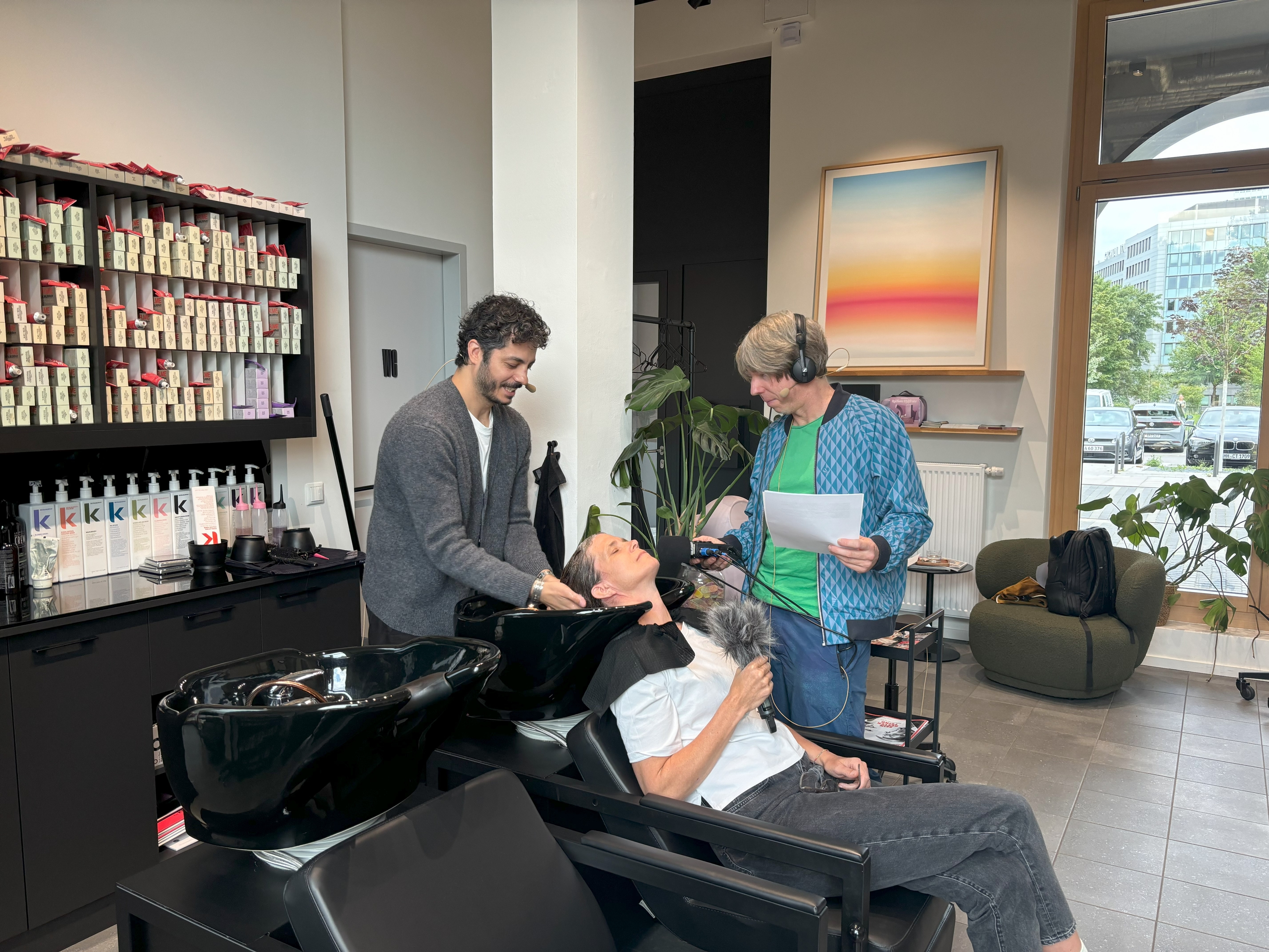 Friseur wäscht Haare, Reporterin mit Mikrofon daneben