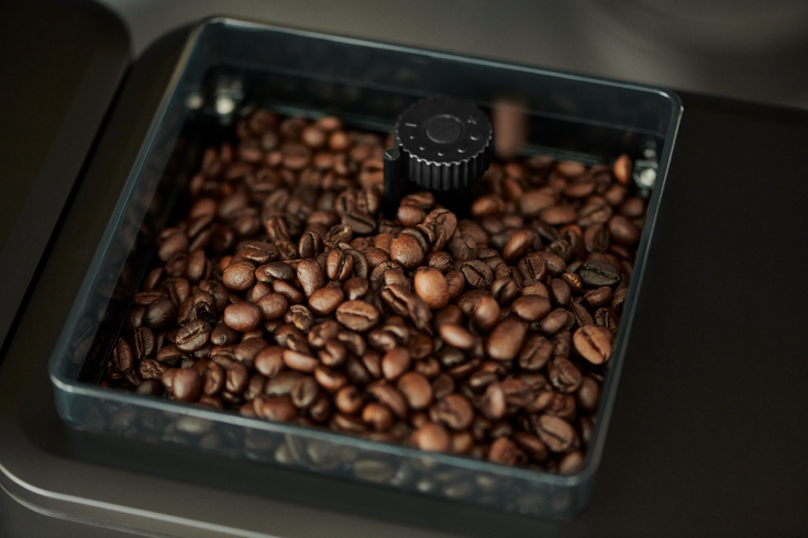 Kaffeebohnen in Mühle mit schwarzem Drehknopf
