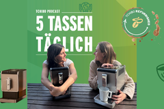Zwei Frauen mit Kaffeemaschinen vor Tchibo-Werbung