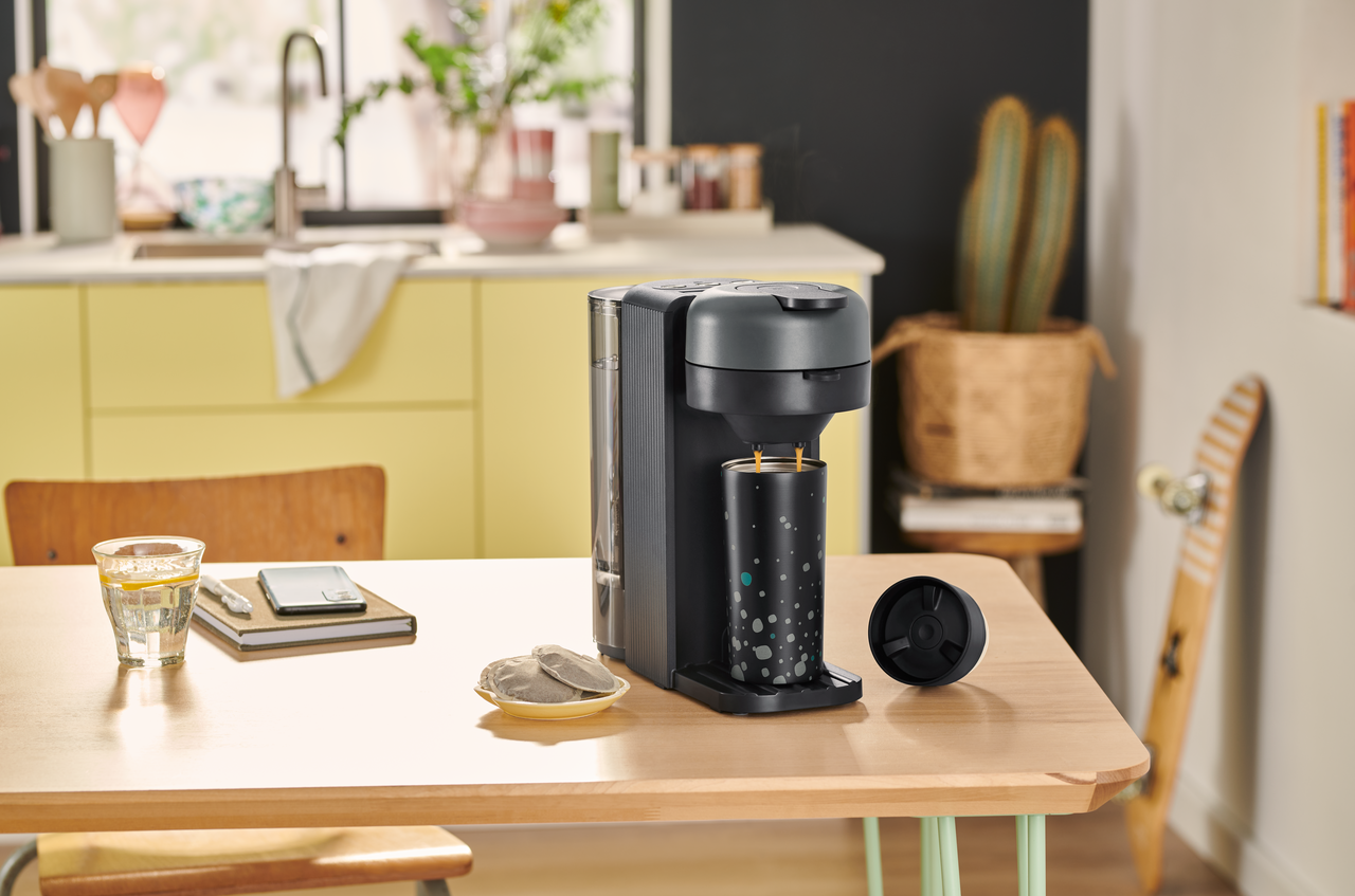 Kaffeemaschine füllt schwarzen Thermobecher in Küche