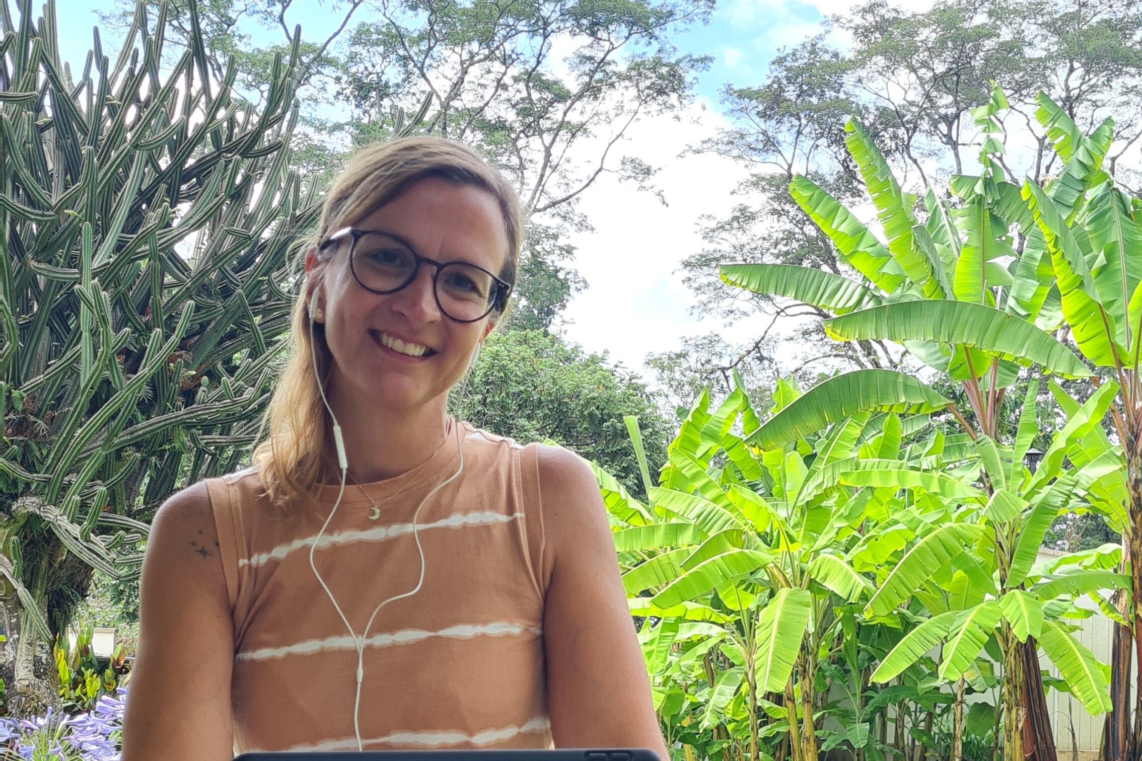 Person mit Tablet im Garten mit Palmen
