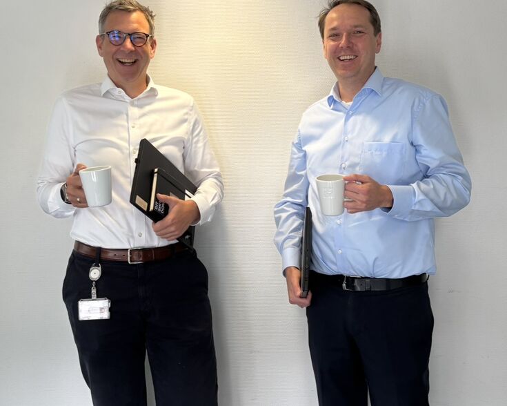 Zwei Büroangestellte mit Kaffee und Laptops