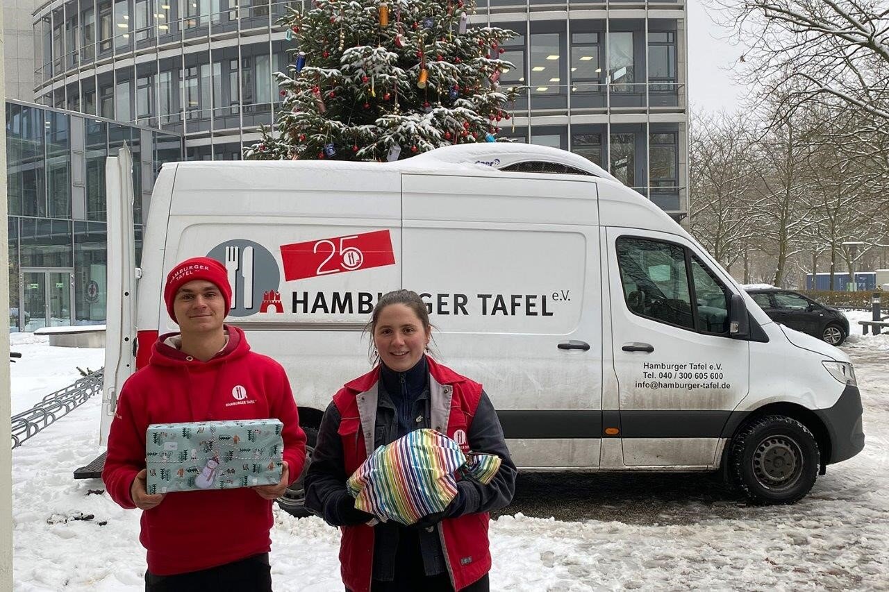 Zwei Helfer mit Geschenken vor Tafel-Transporter
