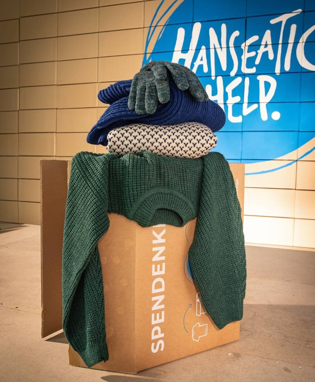 Spendenkarton mit Pullover, Mütze, Kissen und Handschuhen
