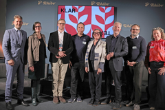 Neun Personen posieren vor Tchibo-Bühne