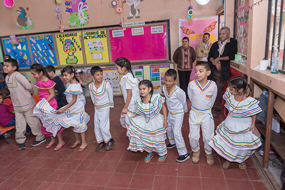 Kinder in traditionellen Kostümen tanzen im Klassenraum
