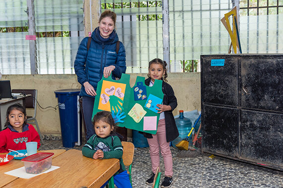 Erwachsene und Kinder zeigen buntes Plakat im Klassenraum