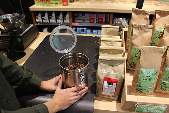 Hände halten Dose mit Kaffeebohnen neben Packungen