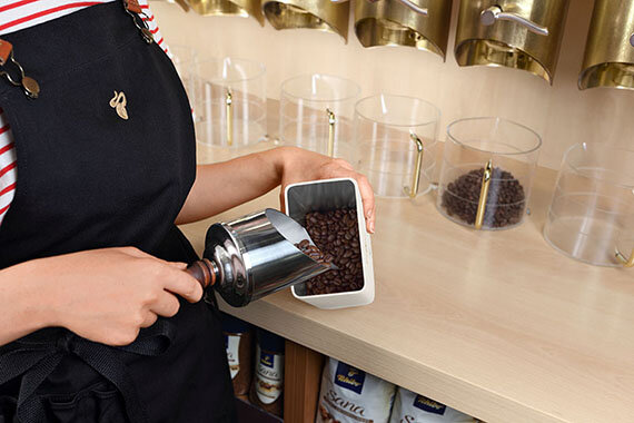 Person füllt Kaffeebohnen in einen Behälter