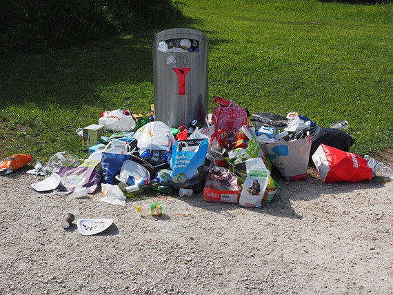 Überfüllter Mülleimer mit verstreutem Abfall
