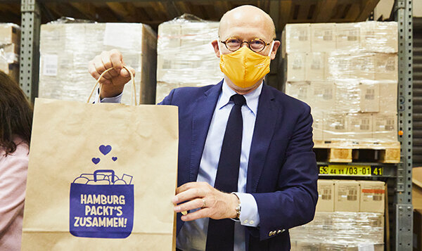 Mann hält Tüte mit Aufdruck „Hamburg packt’s zusammen!“